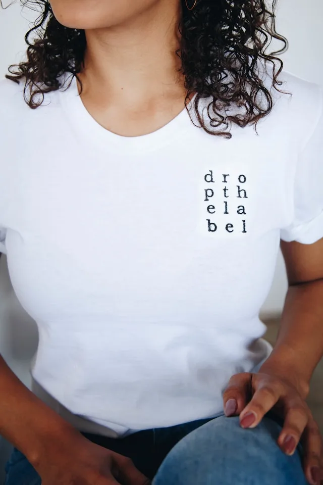 L'image montre un flocage noir personnalisé sur un t-shirt blanc.